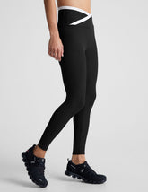 black high-waisted midi length legging with white contrast binding at crossover waistband.